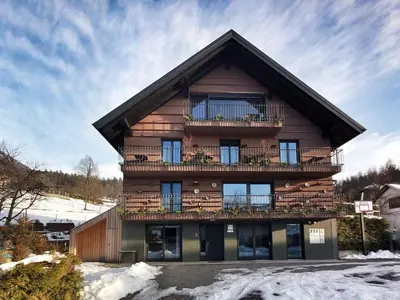a wooden house with a balcony and snow at Bed & Breakfast Base Camp in Križe