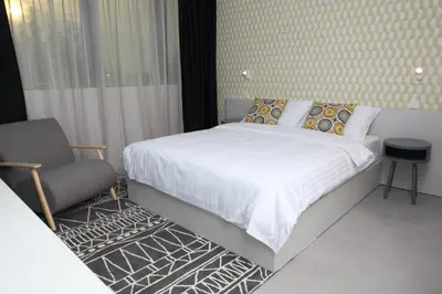 a bedroom with a large bed and a chair at Hotel Cubis in Lendava