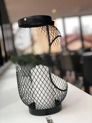 a black wire basket sitting on top of a table at Hotel Cubis in Lendava