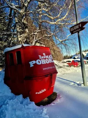 a red dumpster sitting in the snow next to a street at Foxi apartment, Pohorje in Pohorje
