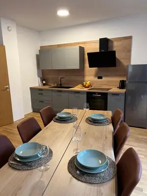 a kitchen with a table with plates and wine glasses at Foxi apartment, Pohorje in Pohorje