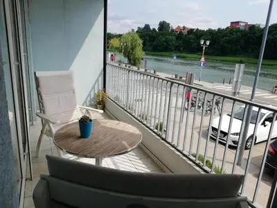a balcony with a table and chairs and a view of a river at Apartment Lent in Maribor