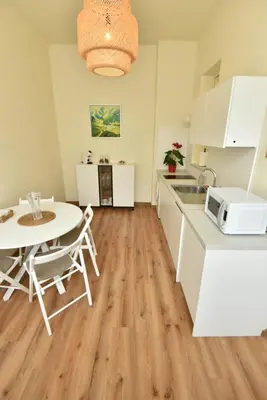 a kitchen with white cabinets and a table and a microwave at Apartment Joja in Ljubljana
