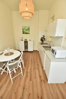 a kitchen with white cabinets and a table and a microwave at Apartment Joja in Ljubljana
