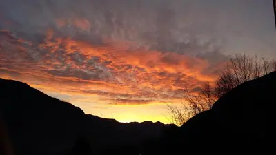 a sunset in the sky over some mountains at Apartment Norma in Bovec