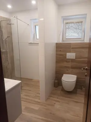 a bathroom with a toilet and a glass shower at The Cottage in Murska Sobota