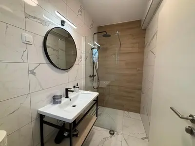 a bathroom with a sink and a shower and a mirror at Apartmaji Čepon in Ljubljana