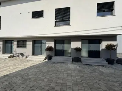 a white building with glass doors and potted plants at Apartmaji Čepon in Ljubljana