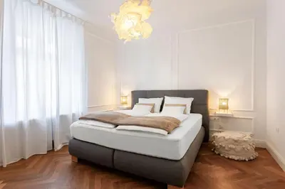 a bedroom with a large bed with a chandelier at MARIANNA'S OLD TOWN RESIDENCE in Ljubljana
