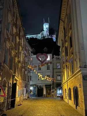 a city street at night with a building with a clock tower at MARIANNA'S OLD TOWN RESIDENCE in Ljubljana