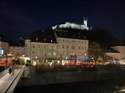 a building with people walking on a bridge at night at MARIANNA'S OLD TOWN RESIDENCE in Ljubljana