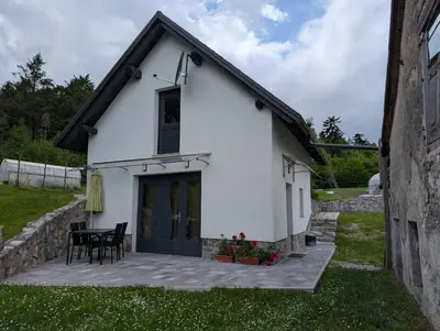 a small white building with a patio and a table at TOMO 2 in Postojna