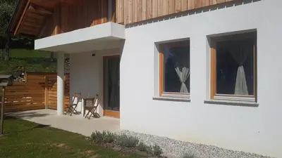 a white house with two windows and a patio at LARCH HOUSE in Cerklje na Gorenjskem