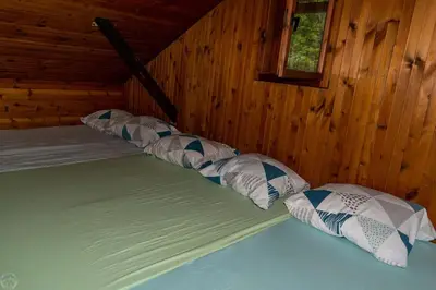 a bed with four pillows in a wooden room at Home Puščava in Kranj