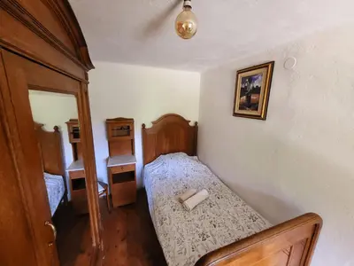 a small bedroom with a bed and a mirror at Čukova bajta in Most na Soči
