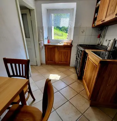 a kitchen with a stove and a table and a window at Čukova bajta in Most na Soči