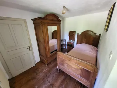 a bedroom with a bed and a dresser and a door at Čukova bajta in Most na Soči