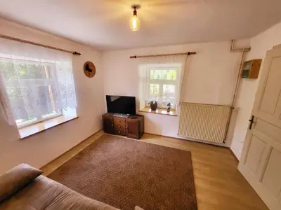 a living room with a couch and a tv and windows at Čukova bajta in Most na Soči