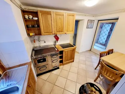 a kitchen with wooden cabinets and a stove top oven at Čukova bajta in Most na Soči