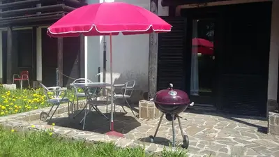 a grill and a pink umbrella on a patio at Apartma Rogla Gaber 110 in Zreče