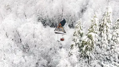 an aerial view of a cabin in the middle of a snow covered forest at Cozy A-Frame Retreat Near Ljubljana With Hot Tub in Cerklje na Gorenjskem