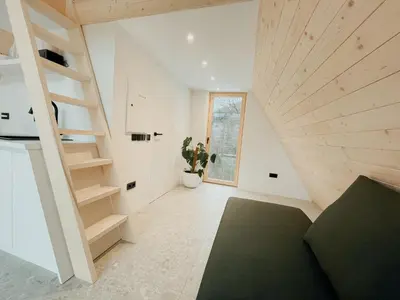 a living room with a staircase in a house at Cozy A-Frame Retreat Near Ljubljana With Hot Tub in Cerklje na Gorenjskem