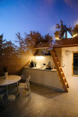 a kitchen with a table and a sink and a stove at Cozy A-Frame Retreat Near Ljubljana With Hot Tub in Cerklje na Gorenjskem