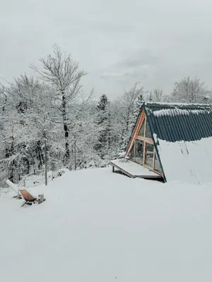 a cabin with snow on the ground in front of it at Cozy A-Frame Retreat Near Ljubljana With Hot Tub in Cerklje na Gorenjskem