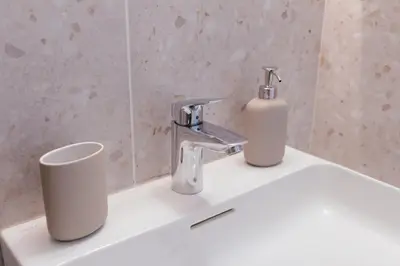 a bathroom sink with two faucets and a cup at Luxury 2 bedroom NEW apartment with private parking in Ljubljana
