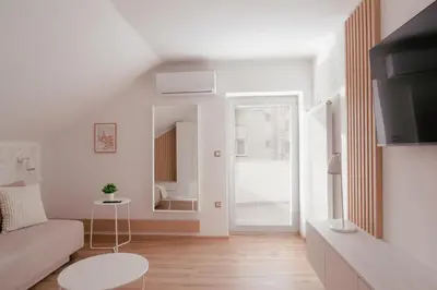 a white living room with a couch and a mirror at Luxury 2 bedroom NEW apartment with private parking in Ljubljana