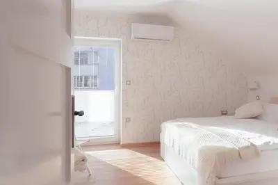 a white bedroom with a bed and a window at Luxury 2 bedroom NEW apartment with private parking in Ljubljana