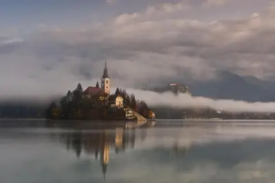 a castle on an island in the middle of a lake at Farm Stay Dolinar Krainer in Bohinjska Bela