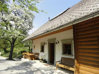 a house with a bench next to a table at Farm Stay Dolinar Krainer in Bohinjska Bela