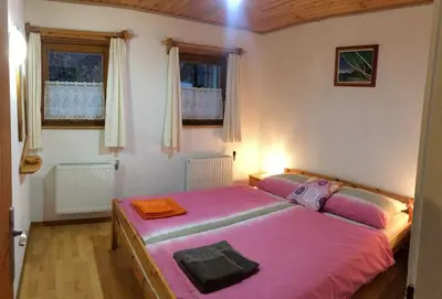 a bedroom with a bed with pink sheets and windows at Apartments Torkar in Bled