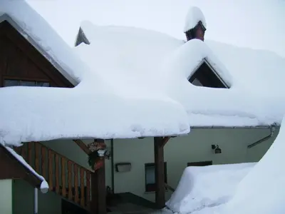 a house covered in snow on the stairs at Apartments Torkar in Bled