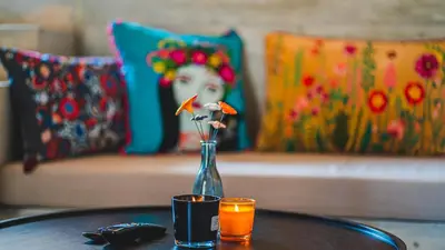 a vase with flowers on a table with a couch at Premium Gardenguesthouse Mlinar with Pool & Sauna in Fokovci