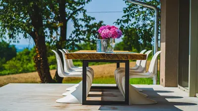 a table with a vase of pink flowers on it at Premium Gardenguesthouse Mlinar with Pool & Sauna in Fokovci