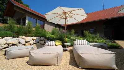 a patio with two couches and an umbrella at Premium Gardenguesthouse Mlinar with Pool & Sauna in Fokovci