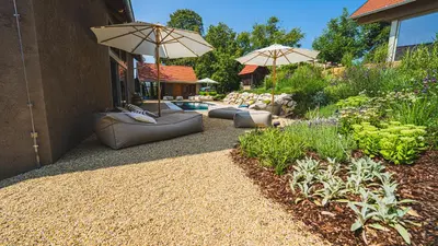 a patio with two umbrellas and a swimming pool at Premium Gardenguesthouse Mlinar with Pool & Sauna in Fokovci