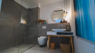 a bathroom with a sink and a toilet and a mirror at Premium Gardenguesthouse Mlinar with Pool & Sauna in Fokovci