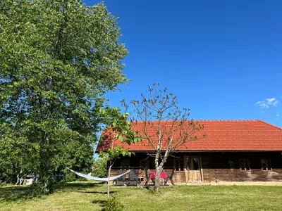 a house with a red roof and a hammock in front of it at Hisa Suzana in Črnomelj