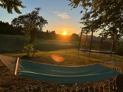 a hammock in a field with the sunset in the background at Hisa Suzana in Črnomelj