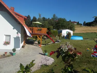 a house with a deck next to a yard at Apartment Rozika in Slovenj Gradec