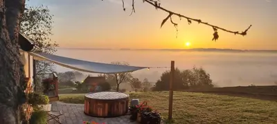 a sunset over a field with a table and a barrel at Hiška pod črešnjo in Rogašovci