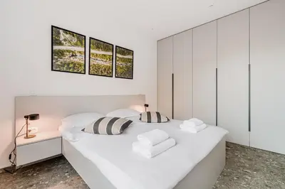 a white bedroom with a large white bed with two pillows at Adventure Oasis Bovec in Bovec