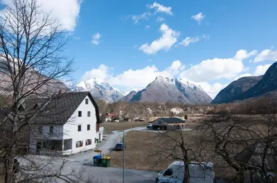a white house with mountains in the background at Guest house Vila Korošec in Bovec