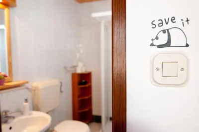 a bathroom with a toilet and a sign that says save it at Guest house Vila Korošec in Bovec