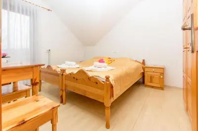 a bedroom with a wooden bed and a table at Guesthouse Kaučič in Benedikt v Slovenskih Goricah