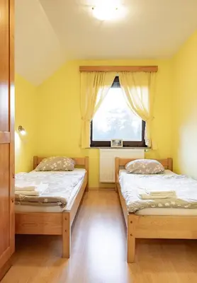 two beds in a room with yellow walls and a window at Apartments Jasa in Mozirje