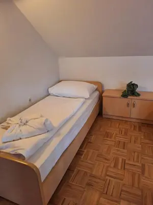 a bed in a small room with wooden floors at Župnijski apartmaji in Dolenjske Toplice